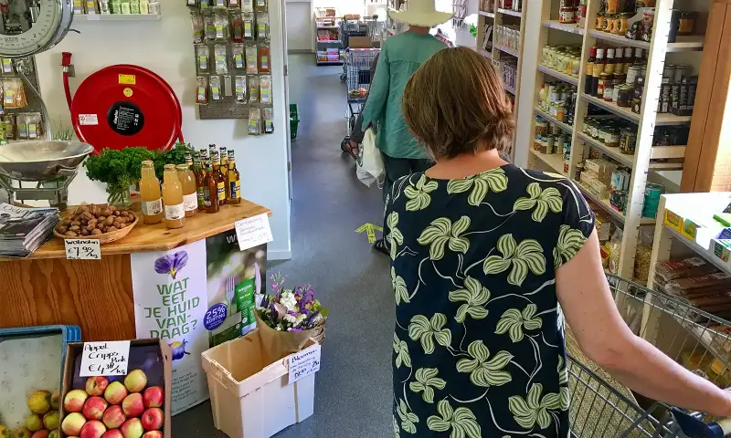 Winkelend publiek langs schappen vol met natuurvoeding